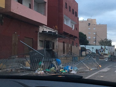 Imagen tomada por la Cadena Ser Melilla ayer a primera hora, en la que se pueden ver dos contenedores volcados en la Carretera de Hidum, uno de ellos vallado, y basuras esparcidas (FOTO CADENA SER MELILLA)