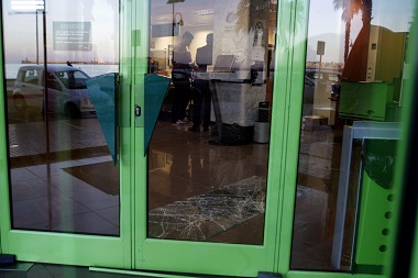 El cristal de la puerta, hecho añicos en el suelo mientras la Policía toma huellas dentro del banco