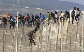Inmigrantes encaramados en la valla fronteriza de Melilla.
