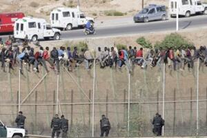 Inmigrantes encaramados a la valla fronteriza de Melilla en su intento de entrar a España