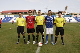 Juan Peña Varela, en el encuentro de Liga de la temporada 2013-14, con los capitanes de la U.D. Melilla y de La Roda