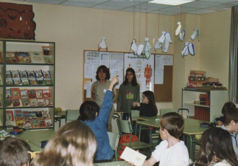 En la imagen, un grupo de escolares en clase con una profesora