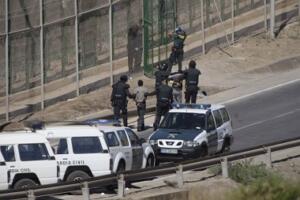Guardias civiles entregan a un inmigrante en la valla de Melilla
