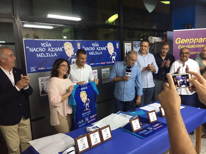 La profesora del Colegio Prácticas, autora de la caricatura de la Peña, recibe una camiseta de su integrante y jugador del Melilla, Nacho Aznar