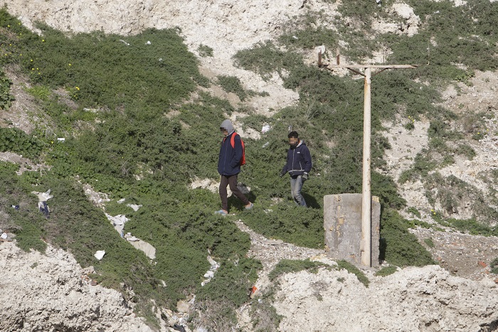 Dos inmigrantes adolescentes, caminando por las rocas de Melilla la Vieja mientras la Autoridad Portuaria estaba presentando las medidas de refuerzo de la seguridad en el espaldón