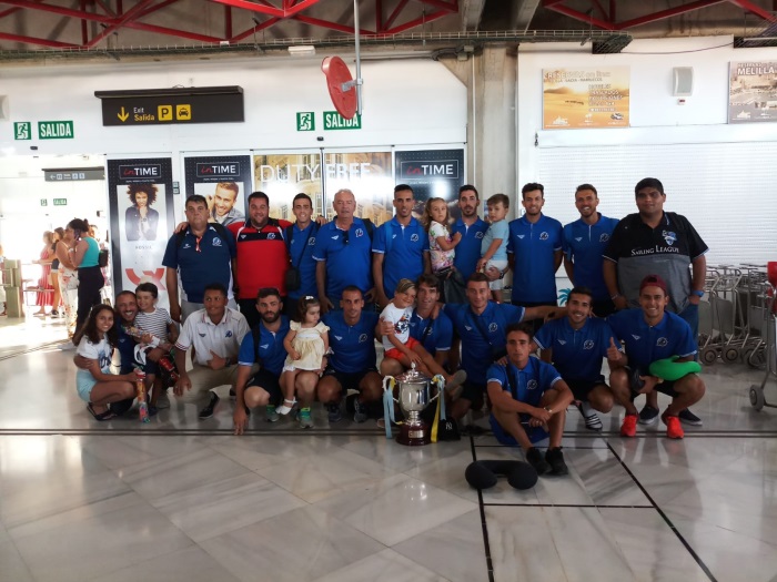 Los integrantes del combinado de Melilla posando todos juntos con la copa, nada más aterrizar en el aeropuerto de nuestra ciudad