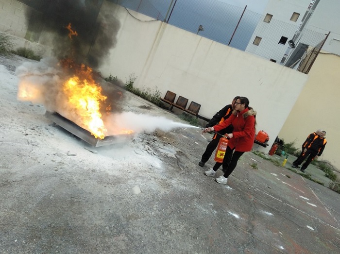 Una asistente realizando una prueba práctica sobre la extinción de un fuego con un extintor