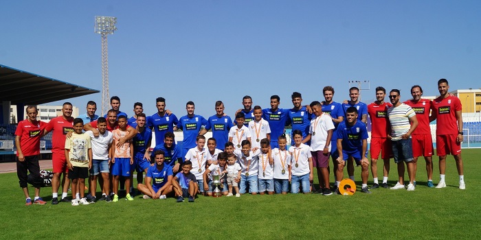 Los jugadores Alevines de la U.D. Melilla posan con la Copa de campeones con los componentes del primer plantel de la Segunda B