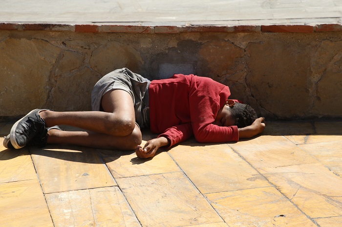 Fotografía de un menor no acompañado tirado en el suelo de una plaza melillense