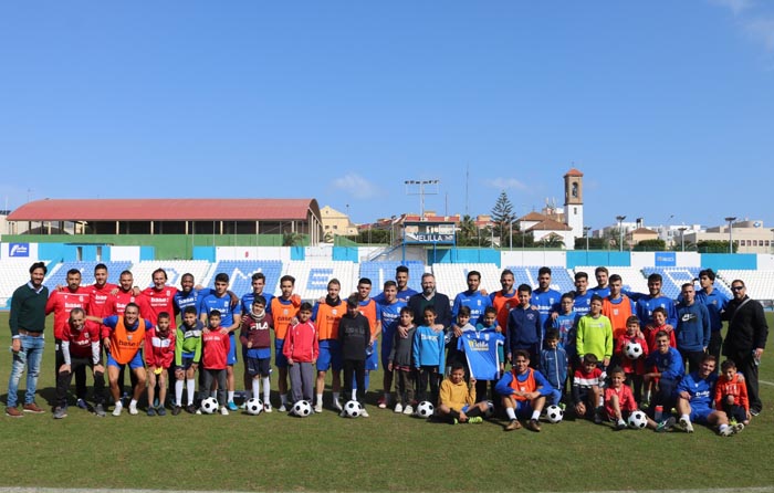 Foto de familia de los componentes de la U.D. Melilla con los niños del Centro Asistencial de Melilla durante la visita de ayer al Estadio Álvarez Claro