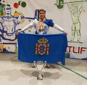 Ismael Jamali posa con la bandera de la Ciudad de Melilla, con sus 3 medallas de oro y la copa de campeón