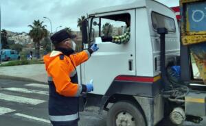 Un miembro de Protección Civil entrega una mascarilla a un conductor