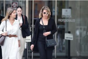 Dos mujeres saliendo de un edificio, una de ellas con gafas de sol