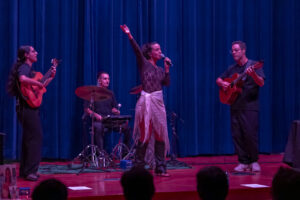 Artista actuando en el Iwa Fest en Melilla con músicos en el escenario.