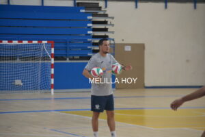 Entrenador Alberto Rodríguez sosteniendo pelotas de voleibol en el gimnasio