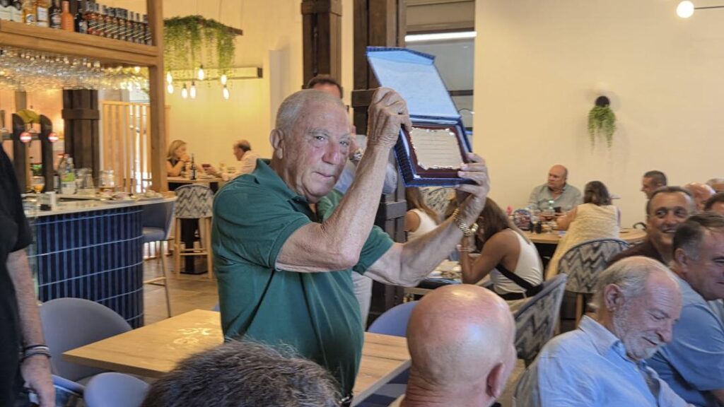 Hombre sosteniendo un reconocimiento en la reunión del balonmano melillense