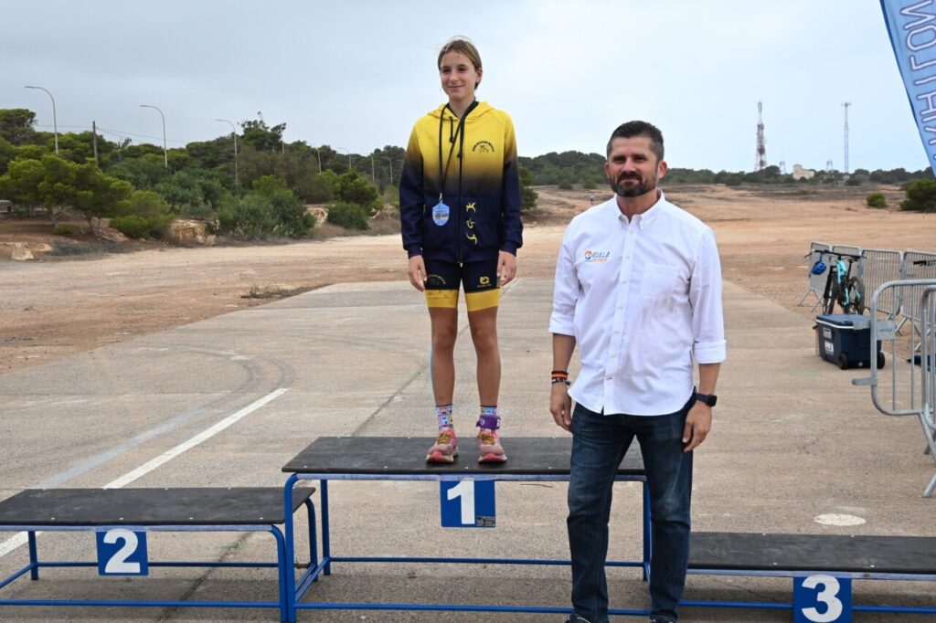 Ganadora del Duatlón Cros TriMelilla 2025 en el podio con medalla.