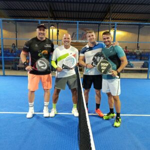 Cuatro jugadores de pádel posando en la cancha tras un partido.