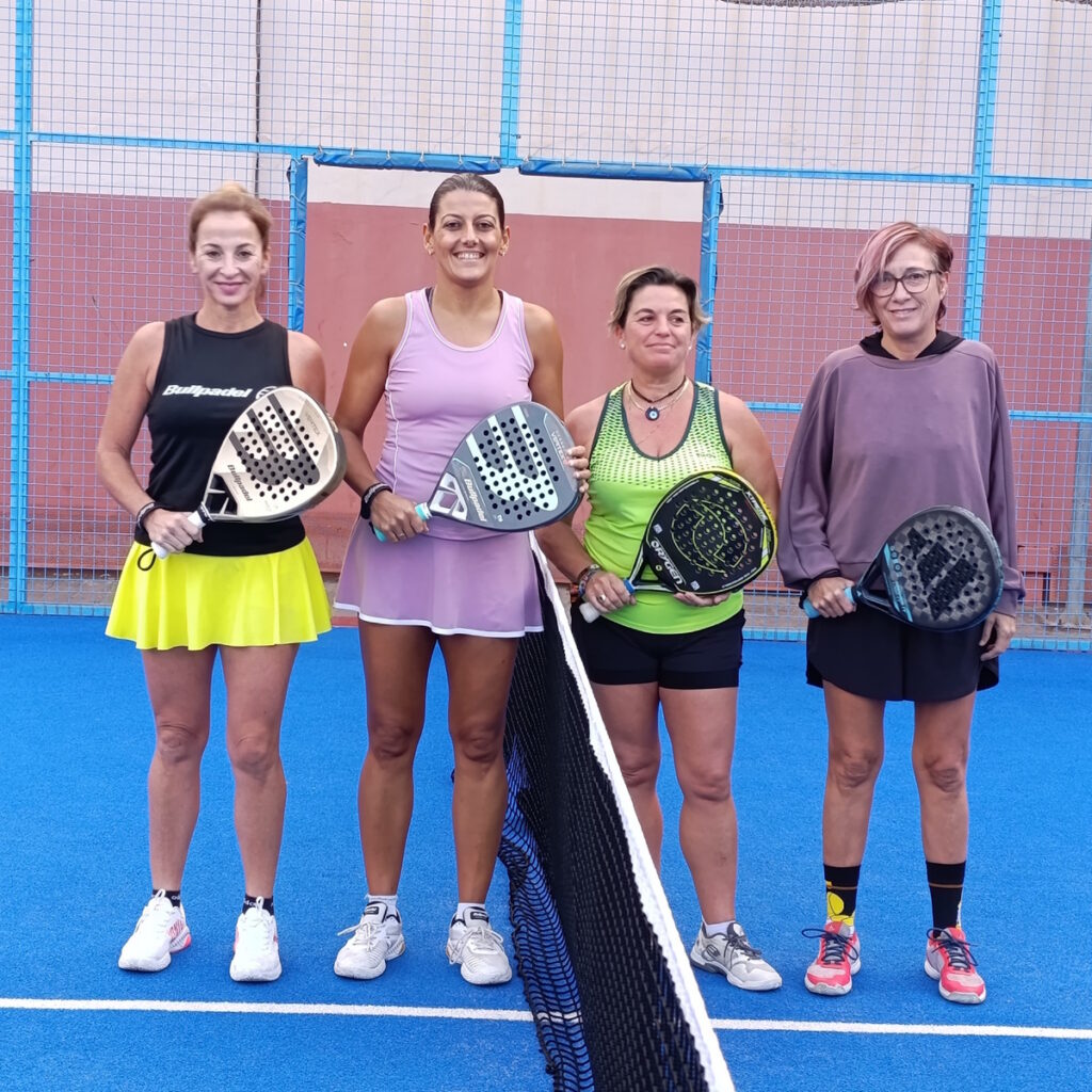 Cuatro mujeres posando con palas de pádel en una cancha