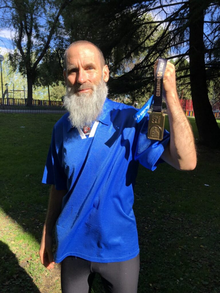 Gustavo Castro sosteniendo su medalla tras completar el maratón
