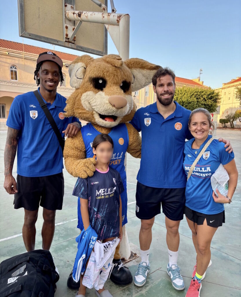 Jugadores del Club Melilla Baloncesto con un niño y una mascota en una cancha