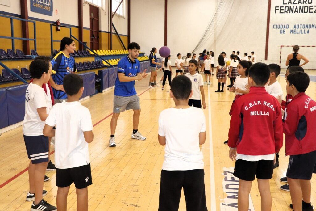 Jugadores del MCD La Salle interactuando con alumnos del CEIP Real en un pabellón deportivo.