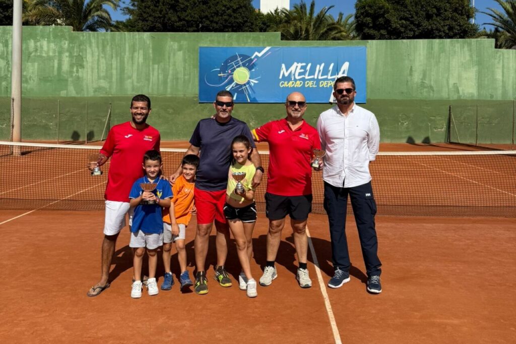 Jugadores y niños posando con trofeos en el torneo de tenis
