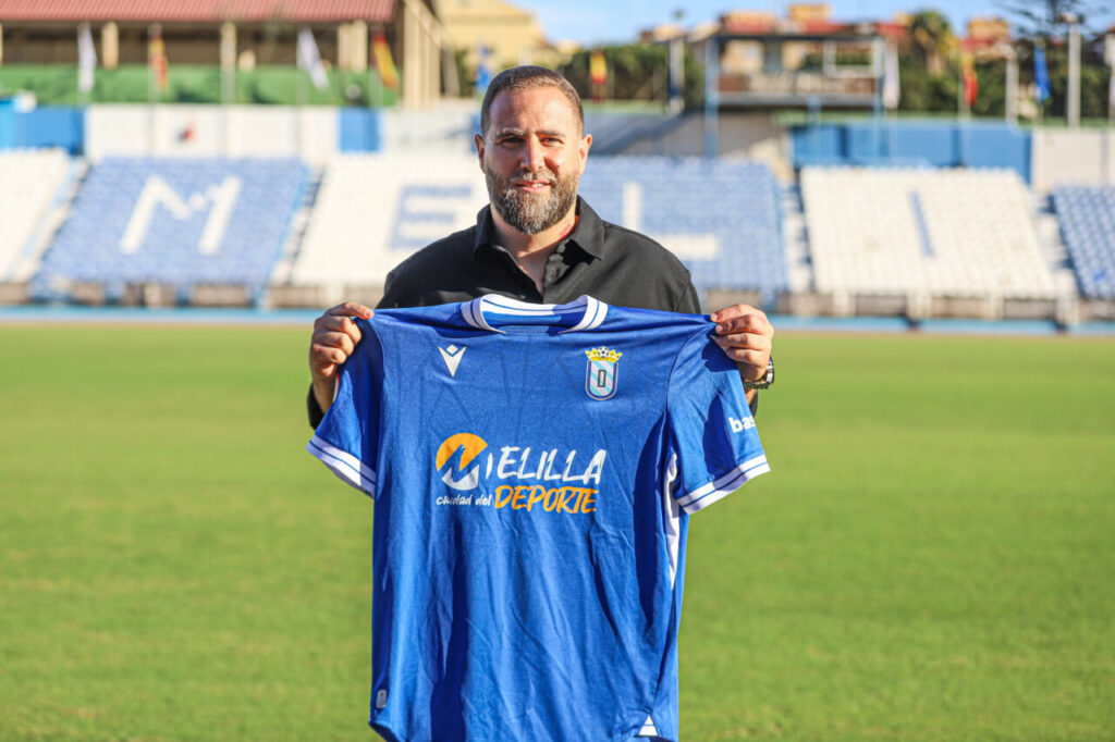 Javi Motos sosteniendo la camiseta de la U.D. Melilla en el estadio