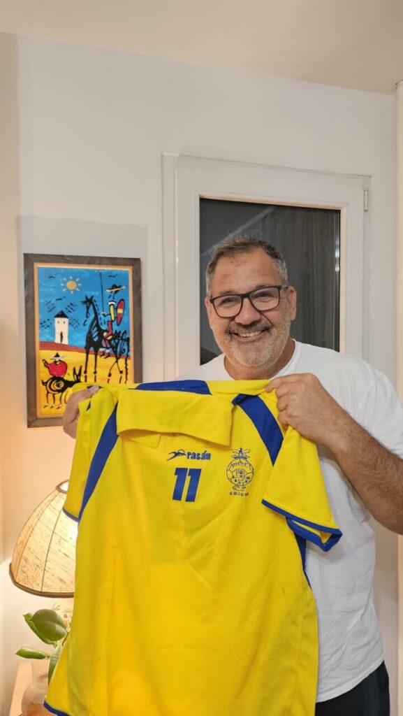 Sasa Kuburovic sosteniendo una camiseta del Ebidem Melilla con una sonrisa