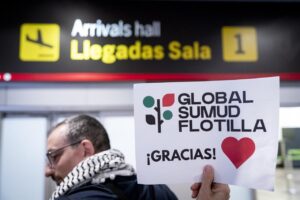 Persona sosteniendo un cartel de Global Sumud Flotilla en el aeropuerto
