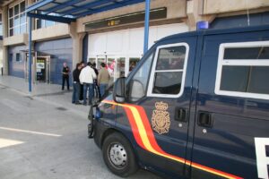 Vehículo policial en la entrada del aeropuerto de Melilla con personas en el fondo.