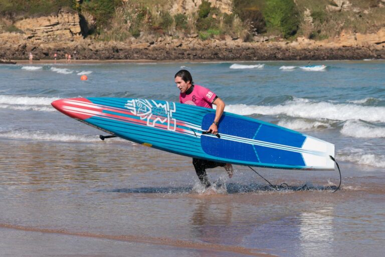 Antonio Castellanos corriendo con su tabla de paddle surf en la playa