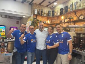Grupo de personas en la cafetería Brisamar vistiendo camisetas de la U.D. Melilla.