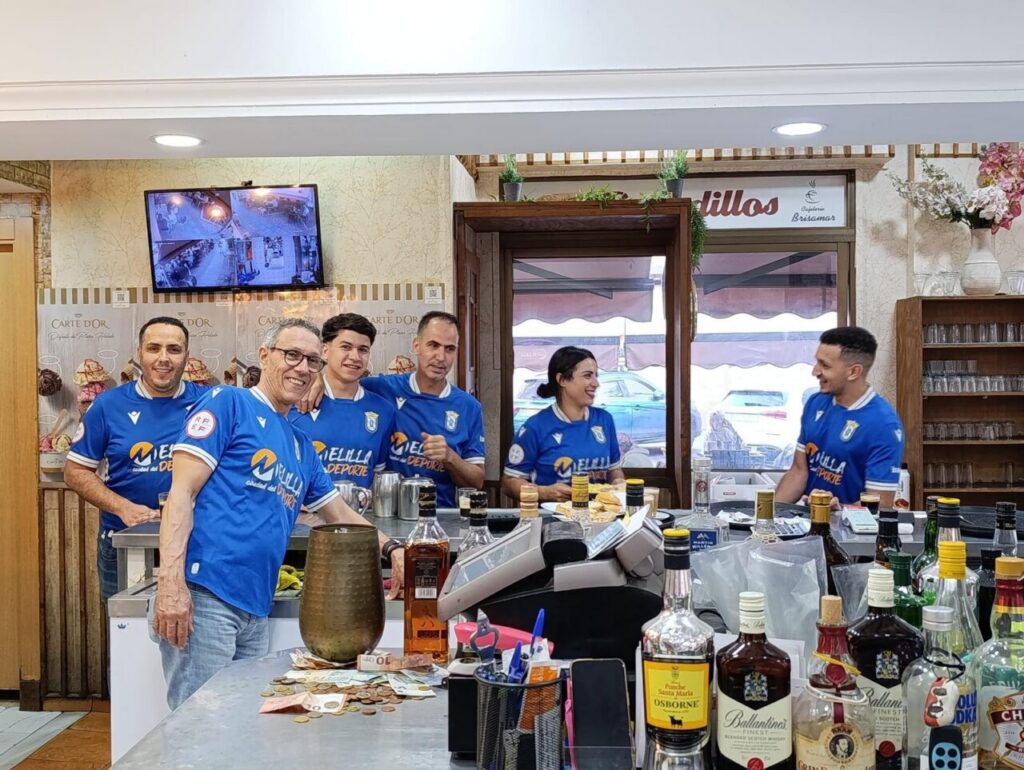 Empleados de la cafetería Brisamar luciendo camisetas de la U.D. Melilla