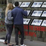 Pareja observando anuncios de viviendas en una inmobiliaria