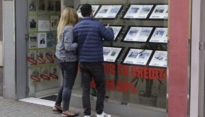 Pareja observando anuncios de viviendas en una inmobiliaria