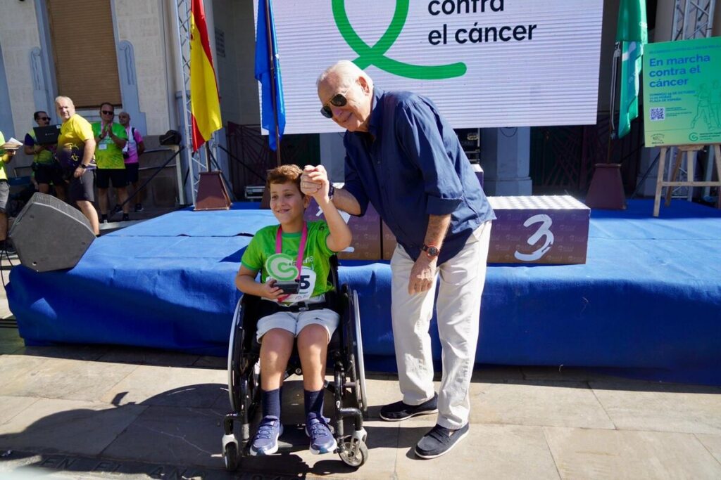Niño en silla de ruedas recibiendo un trofeo en la carrera contra el cáncer