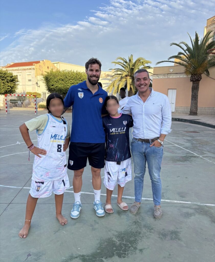 Jugadores del Club Melilla Baloncesto con niños en una cancha