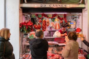 Clientes comprando carne en un mercado local con productos frescos