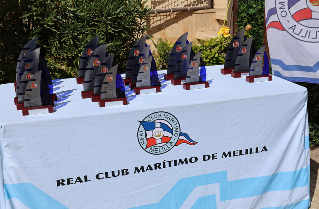 Trofeos de la V Regata Delegación de Defensa en Melilla sobre una mesa.