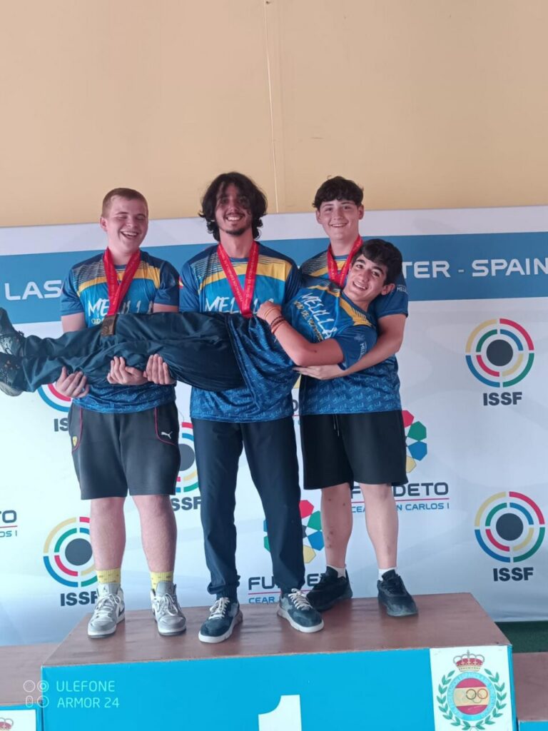 Cuatro jóvenes del equipo junior masculino sosteniendo a uno de sus compañeros en el podio.