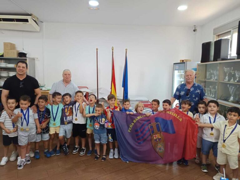 Grupo de niños con medallas y bandera de la Peña Barcelonista