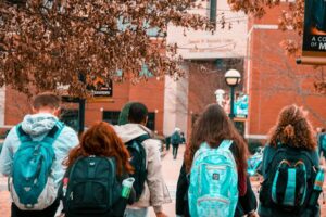 Grupo de estudiantes caminando hacia la universidad con mochilas.