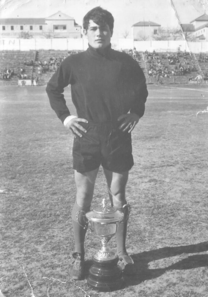 Joven futbolista posando con un trofeo en el campo