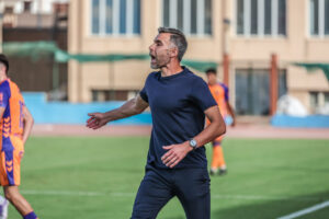Entrenador de la UD Melilla dirigiendo a su equipo en el campo.