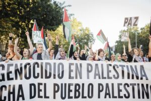 Multitud de personas en manifestación por Palestina con pancartas y banderas.