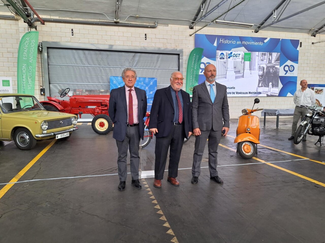 Tres hombres posando junto a vehículos históricos en un evento en Melilla.