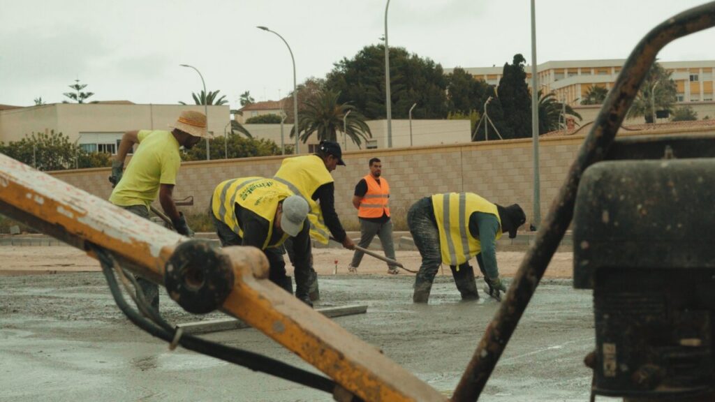 Trabajadores de construcción aplicando cemento en un proyecto de Promeco 2000.
