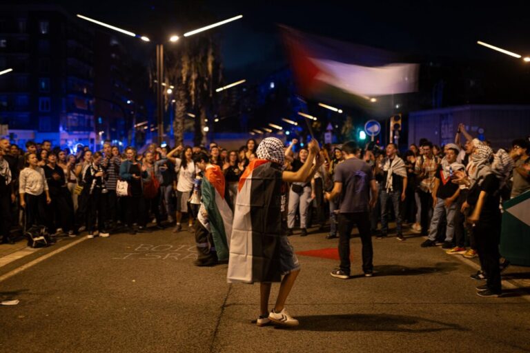 Manifestantes en Israel sosteniendo banderas durante una protesta nocturna.