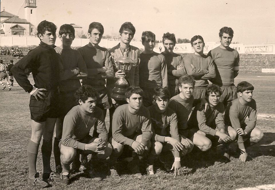 Equipo de fútbol Real A Juvenil posando con un trofeo en el campo